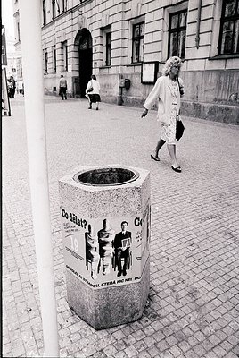 Urban trash bin with Czech/Slovak text ("Co dělat?" + silhouettes) on cobblestone street. Mid-20th century European architect...