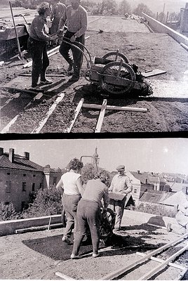 Mid-20th century urban construction crew using a manual asphalt roller on a freshly paved roadway. Workers in casual workwear...