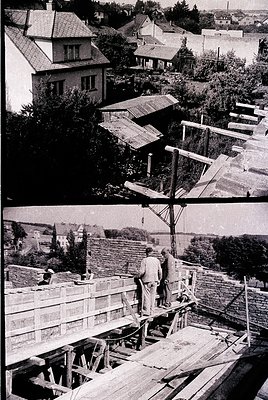 Mid-20th century construction site featuring wooden scaffolding and roof framing. Two workers in the lower image appear to se...