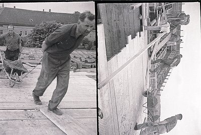 Mid-20th century construction scene: Workers in heavy-duty overalls push a wheeled cart on wooden planks, likely a building s...