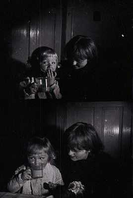 Vintage split-screen photo of two children drinking from ceramic mugs at a table, likely mid-20th century. Dark, grainy monoc...