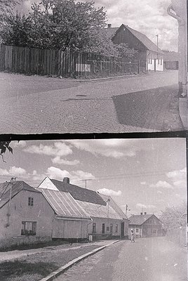 Vintage black-and-white street scene featuring modest Soviet-era brick houses with gable roofs and simple window designs. Cob...