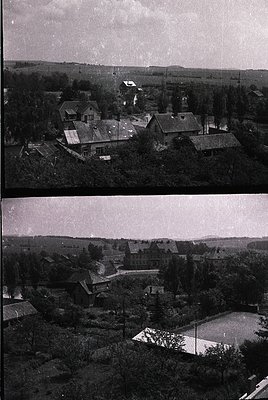 Aerial view of a rural village featuring clustered brick and wooden houses with pitched roofs, surrounded by dense greenery a...