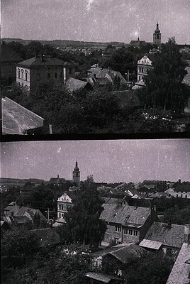 Vintage aerial view of a European village with dense, low-slung wooden architecture and a prominent church steeple. The roofs...