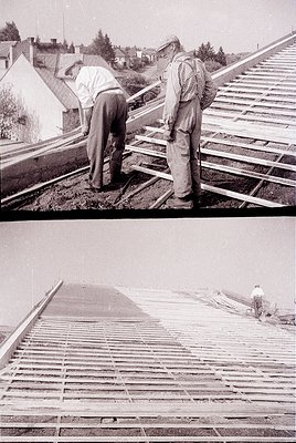 Two workers installing wooden shingles on a sloped roof, mid-20th century. The scene captures manual labor techniques with wo...
