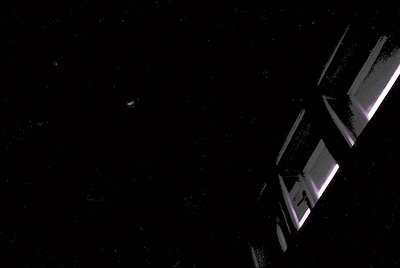 Minimalist geometric sculpture in dark space, featuring angular, reflective metal panels arranged in a staggered, floating fo...