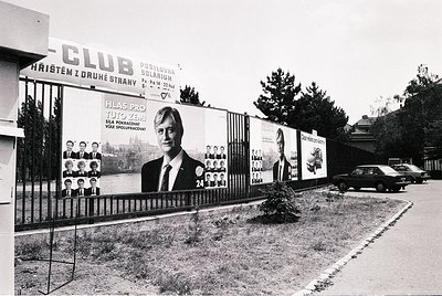 Black-and-white street scene featuring a **1970s-era political campaign billboard** for a candidate named "Tuto Zemana" in Cz...