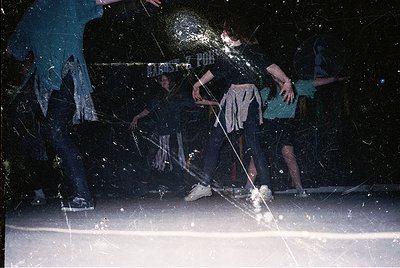 Vintage black-and-white photo capturing an indoor ice hockey game in progress. Players in classic 1970s attire—long-sleeve je...