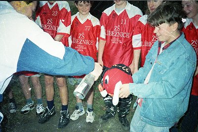 Group huddle with youth soccer team in red jerseys bearing "ZŠ Líbeznice" (likely a Czech school team) and Czech flag scarves...