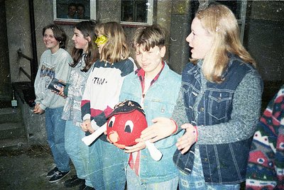 Vintage group photo featuring four teens in casual 1990s attire—flannel shirts, jeans, and a red plush toy (likely a *Troll* ...