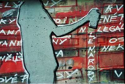 Stencil-style graffiti on weathered brick wall: bold white outline of a hand holding a hammer, with red-painted text in Czech...