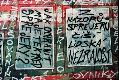 Graffiti-covered wall featuring bold, black text in Czech: *"Jak poznat spravedlnost?"* (left) and *"Nazoru spřeru či lidská ...