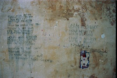 Graffiti-covered concrete wall with Cyrillic inscriptions and a faded sticker. Text appears to be poetic or philosophical, li...