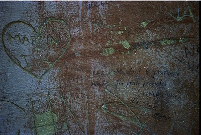 Graffiti etched into weathered concrete wall: heart shape, partial text *"My love..."* and *"forever"* with faded signatures....