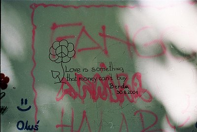Graffiti on a green-painted wall reads: *"Love is something that money can't buy"* (signed "Anny" + date 30.8.2001) alongside...