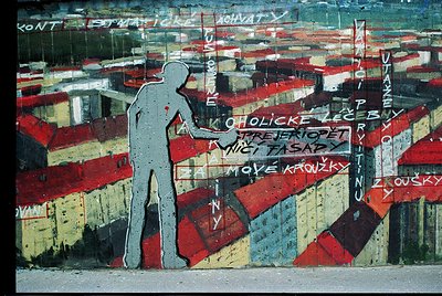 Vibrant mural depicting a silhouetted figure climbing a striped wall with Cyrillic graffiti text in red, white, and blue. Urb...