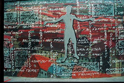 Vibrant mural featuring a stylized human silhouette with outstretched arms against a chaotic backdrop of Czech/Slovak text an...