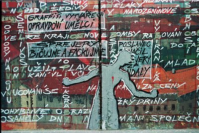 Vibrant street mural featuring bold, layered graffiti in Czech with a central silhouette of a person in motion. Text includes...