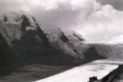Vintage monochrome alpine landscape with jagged peaks and misty valleys. Snow-capped ridges contrast against cloudy skies, ev...