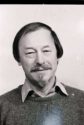 Portrait of a man with a mustache and beard, wearing a collared sweater. Classic 1970s-1980s headshot style, likely for profe...