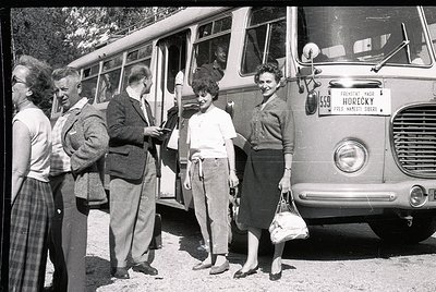 Mid-20th century group boarding a vintage Czech bus, marked "Horecky" with route details. Men in suits, women in 1950s-60s at...