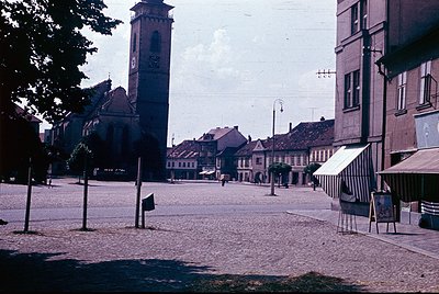 Vintage sepia-toned street scene featuring a prominent clock tower with ornate detailing, likely part of a historic church or...