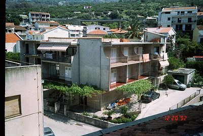 Mid-century Mediterranean residential complex with flat roofs, balconies, and terracotta tiles. Lush greenery and palm trees ...