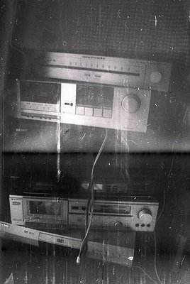 Vintage stereo equipment: Sony cassette deck (bottom) and Portorock tape recorder (top) on a scratched wooden surface, likely...