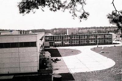 Mid-century Brutalist-style institutional building with raw concrete facade and grid-patterned windows, likely a school or of...