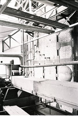 Industrial factory interior featuring exposed brick walls, steel beams, and conveyor systems. Mid-20th century machinery with...