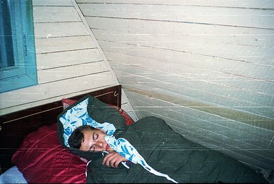 Vintage-style bunk bed with a single sleeper resting on the lower mattress, covered by a patterned blue pillowcase and olive-...