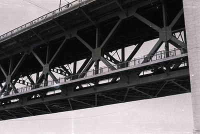Black-and-white industrial bridge featuring riveted steel trusses and walkway railings, likely mid-20th century. Structural d...