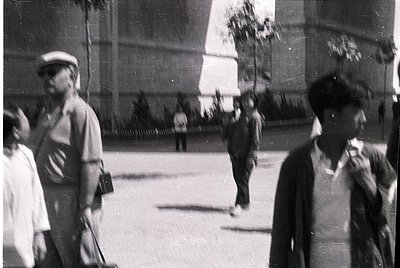 Vintage black-and-white street scene with blurred motion, likely mid-20th century. Urban setting featuring men in 1940s-50s a...
