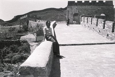 Man poses on Great Wall parapet, 1960s–70s China. Iconic brick fortification with watchtowers and wide walkway. Mid-century t...
