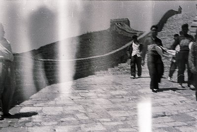 Blurred vintage black-and-white shot of the Great Wall of China with three figures in motion, likely mid-20th century. Stone ...