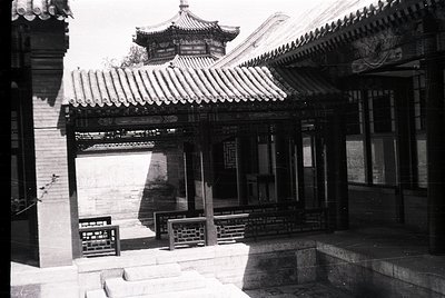 Traditional Chinese courtyard with upturned eaves and tiled roofing, likely from the early-to-mid 20th century. Stone-paved e...