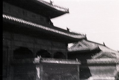 Vintage black-and-white shot of traditional East Asian pagoda-style architecture with tiered, curved eaves and ornate bracket...