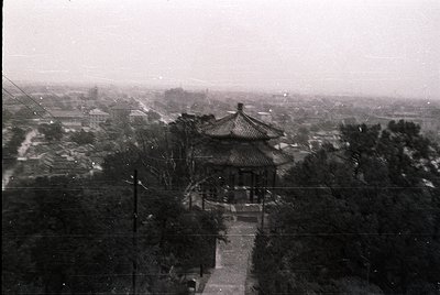 Vintage black-and-white photo of a traditional **Chinese pavilion** with upturned eaves, set atop a stone platform. Dense fol...