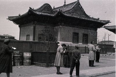 Black-and-white street scene featuring a traditional East Asian-style building with upturned eaves and ornate roof details, l...