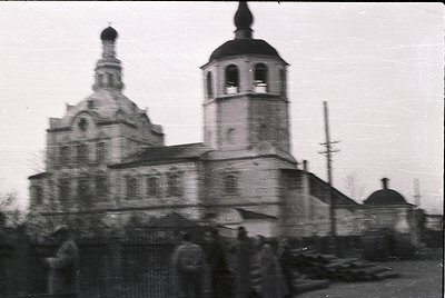 Russian Orthodox church with twin towers and onion domes, likely from the Soviet-era –1970s. Blurred crowd suggests outdoor g...