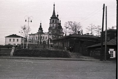 Black-and-white street view of a Russian Orthodox church with twin spires and a central bell tower, featuring intricate detai...