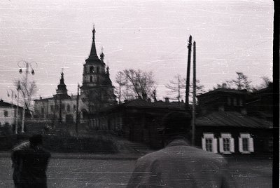 Vintage black-and-white photo of a Soviet-era Orthodox church with a tall, pointed steeple and smaller bell towers, framed by...