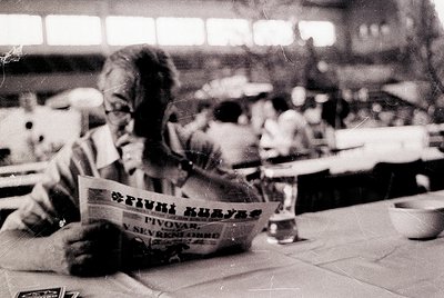 Vintage black-and-white photo of a man reading a Bulgarian newspaper ("Пиво Куявец" by Pivovар "Sevtopore") in a café or rest...