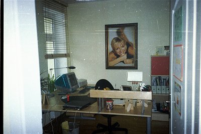 Vintage office space featuring a 1990s-era desk with an Apple IIe computer, framed 1970s-style portrait above, and retro deco...