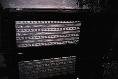 Vintage woven textile with geometric diamond and zigzag patterns, likely a traditional rug or tapestry. Dark, moody lighting ...