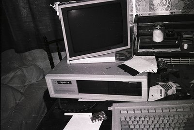 Retro desktop setup featuring a **Commodore Amiga 500** (front) with CRT monitor, keyboard, and mouse. Surrounding clutter in...