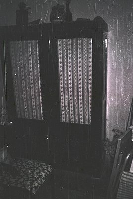 Vintage interior featuring patterned curtains with geometric designs, likely from the 1960s–1970s. Dark wood-framed windows w...