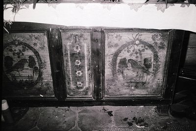 Vintage wooden cabinet with intricate folk-art painted panels, featuring symmetrical floral motifs and bird designs. Center p...