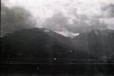 Aerial black-and-white photo of rugged mountain terrain with visible grid lines, likely from early 20th-century surveying or ...