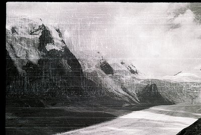 Vintage black-and-white aerial shot of rugged alpine terrain with jagged peaks and steep slopes, likely captured via early fl...